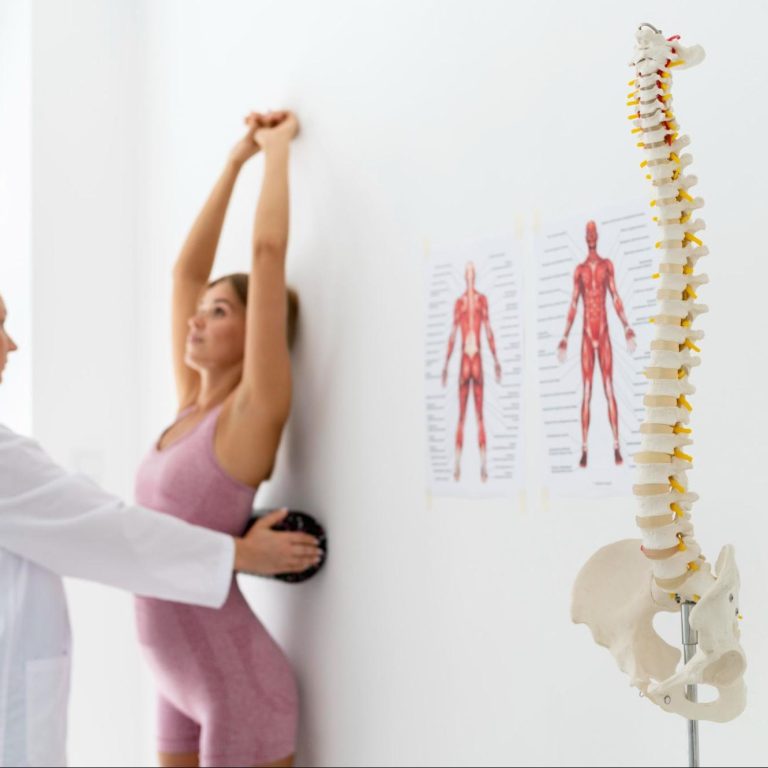 Profissional de saúde a observar o alinhamento postural de uma adolescente durante uma consulta. Caption: A observação postural pode fazer parte da avaliação clínica quando existe suspeita de escoliose.