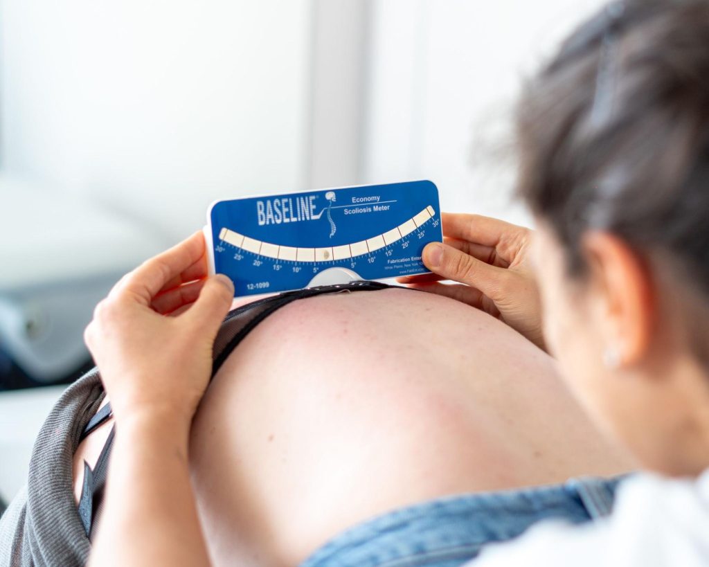 Fisioterapeuta a realizar avaliação clínica da escoliose em adolescente com recurso a escoliómetro.
Caption: A avaliação clínica ajuda a monitorizar a evolução da escoliose e a identificar situações que justificam acompanhamento especializado.